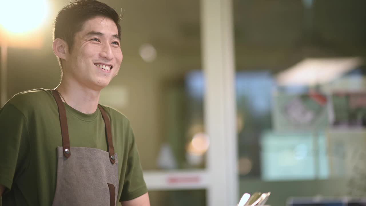 描绘亚洲华人咖啡师在咖啡吧柜台边微笑视频素材