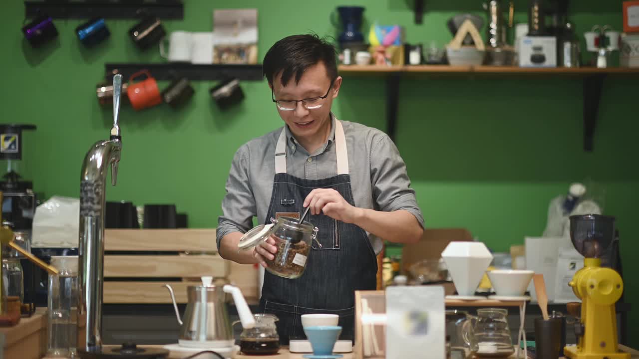 亚洲华人咖啡师在咖啡厅柜台制作咖啡粉视频素材