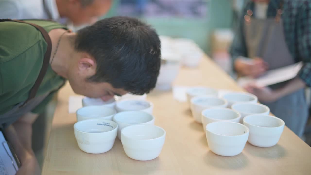 专业的亚洲华人咖啡师，鉴赏家，评分员，表演咖啡杯和他的同事品尝咖啡杯后写在剪贴板上视频素材