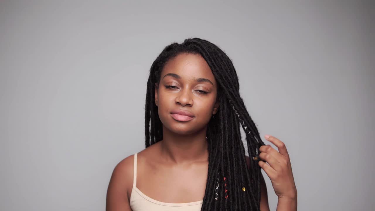 年轻的黑人女孩一边看镜头一边抚摸着自己的头发视频素材