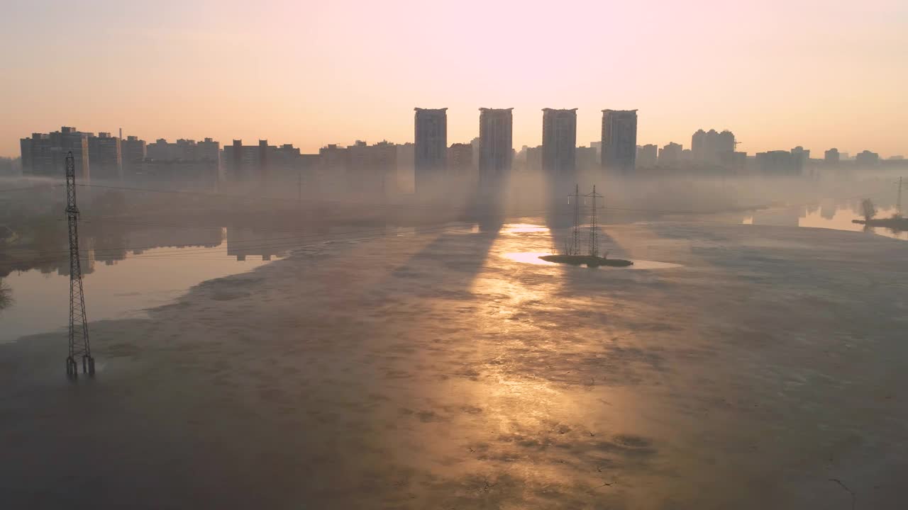 日落冰冻的湖泊或河流，现代城市。电力塔视频素材