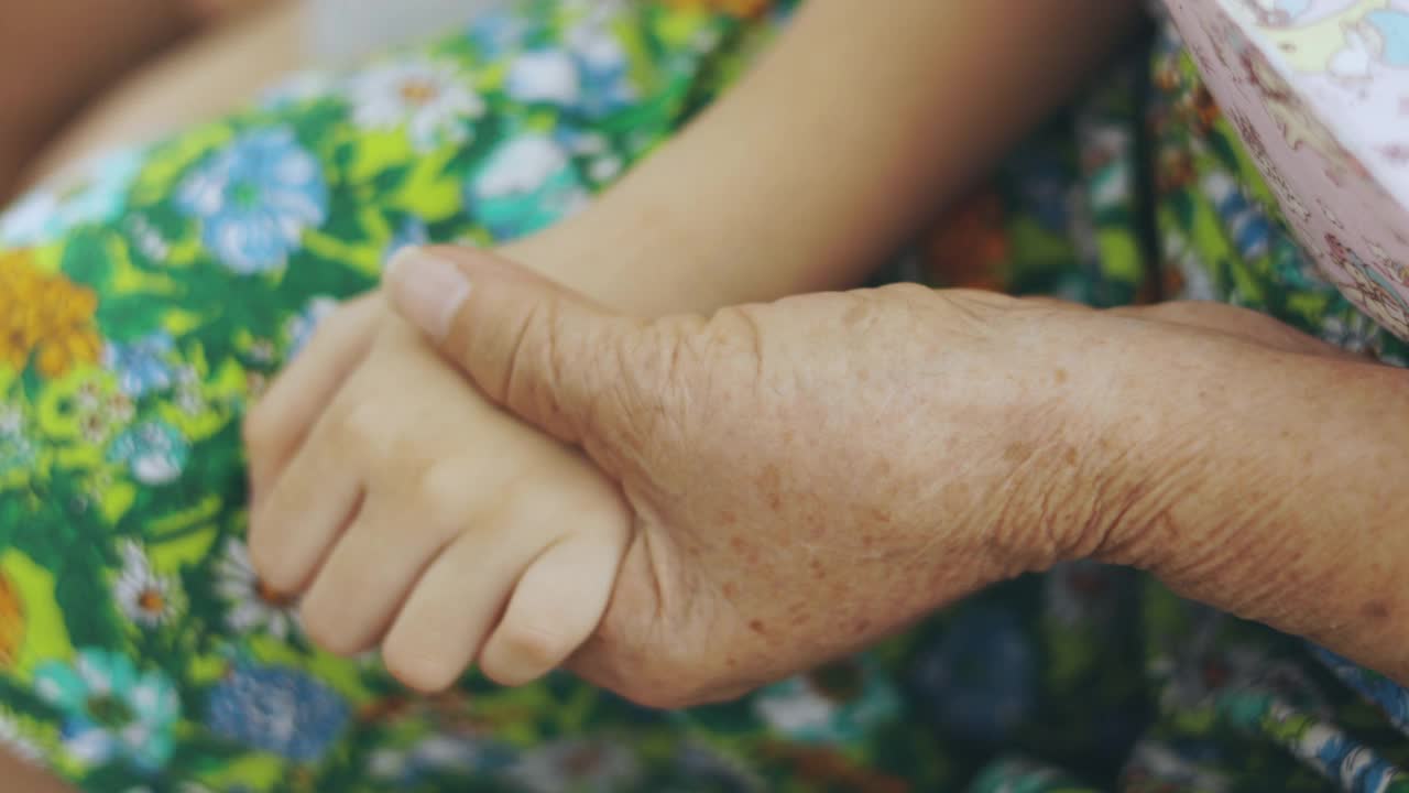 近距离4K的祖母和孙子的手被触摸和抱在一起，显示出人们表达爱和关心的概念，支持和帮助世代之间的家庭关系。视频素材