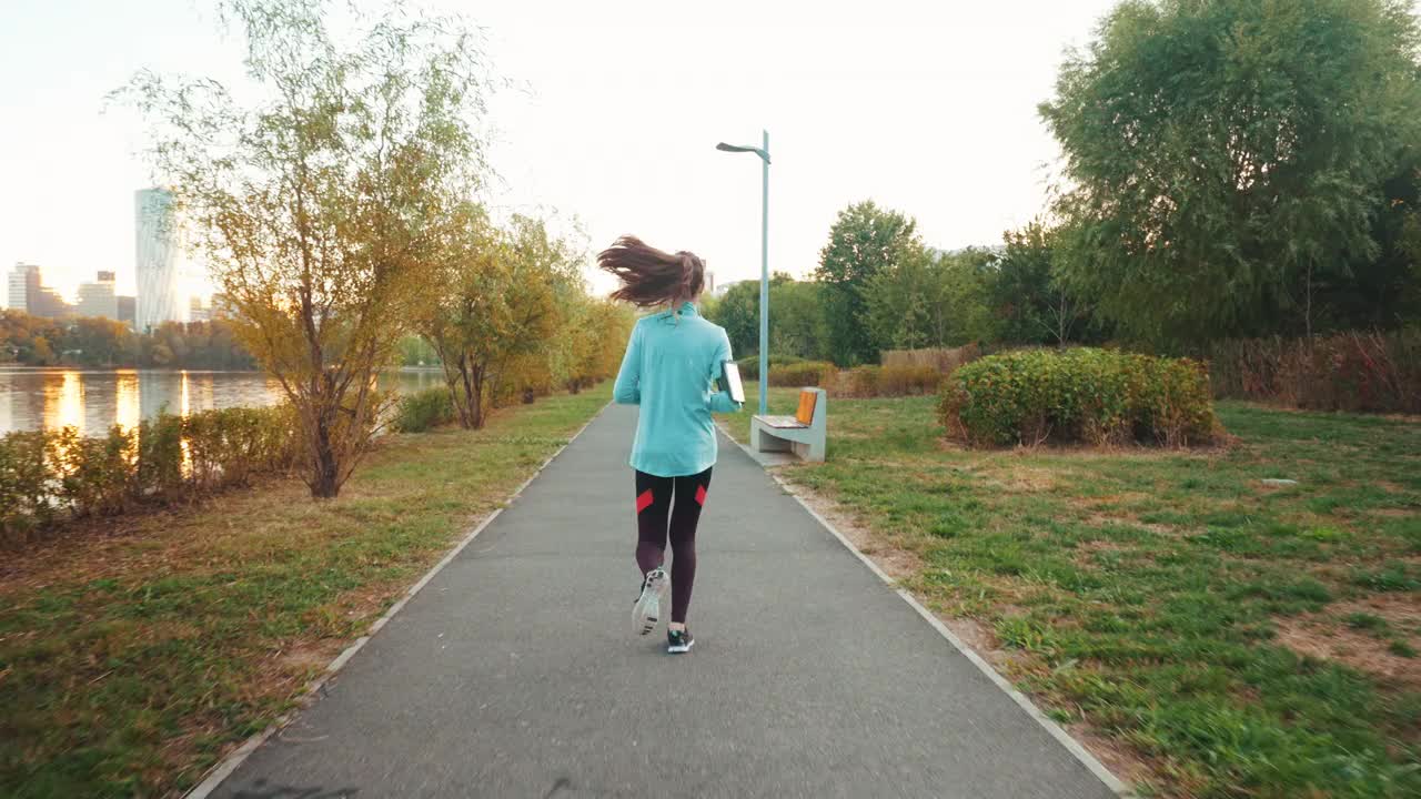 活跃的年轻女性清晨在公园跑步。视频素材