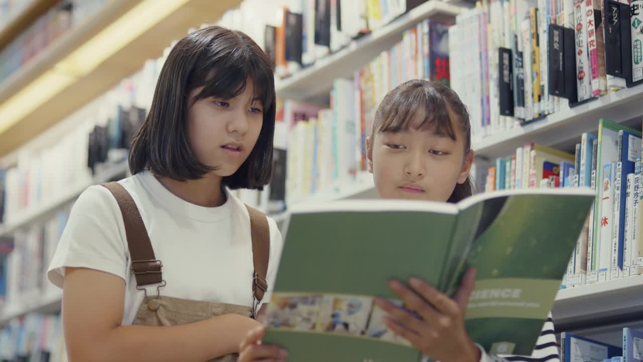 MS两个青春期前的女孩在一起读教科书视频素材