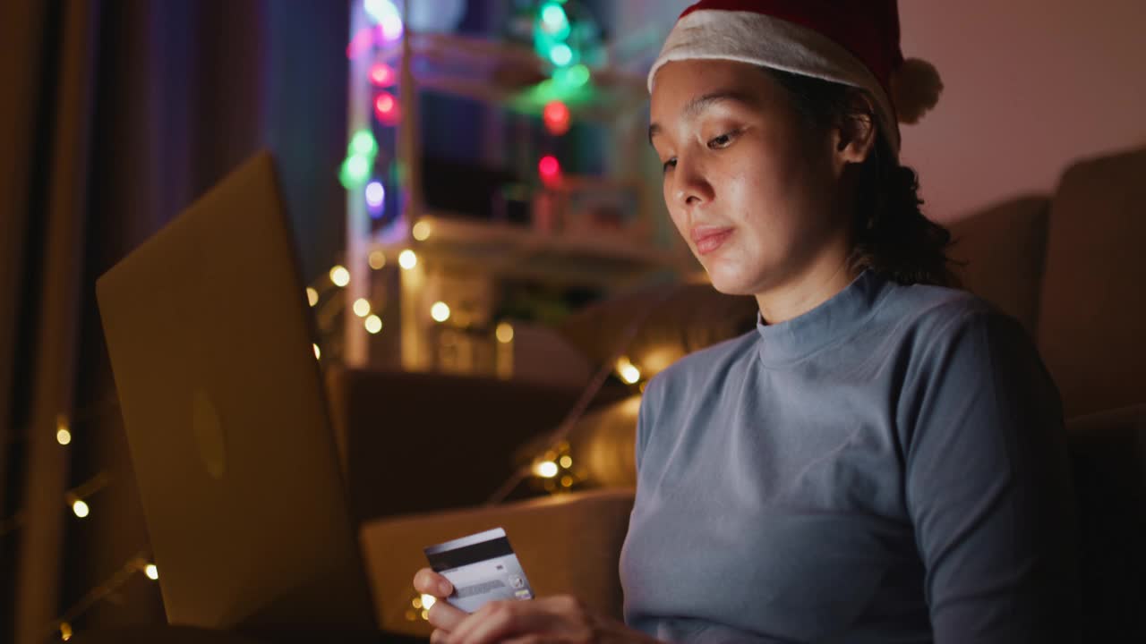 亚洲女人网上购物在她的笔记本电脑在圣诞节在家，手持拍摄视频素材
