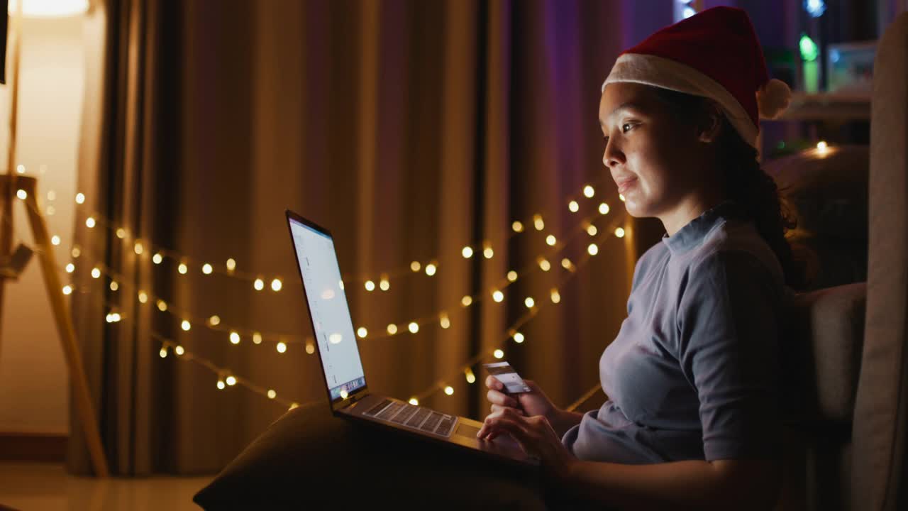 亚洲女人在圣诞节在家用笔记本电脑网上购物视频素材