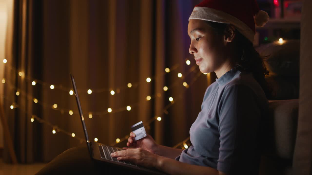亚洲女人在圣诞节在家用笔记本电脑网上购物视频素材