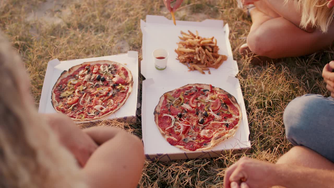 一群朋友在海滩上吃素食披萨和薯条视频素材