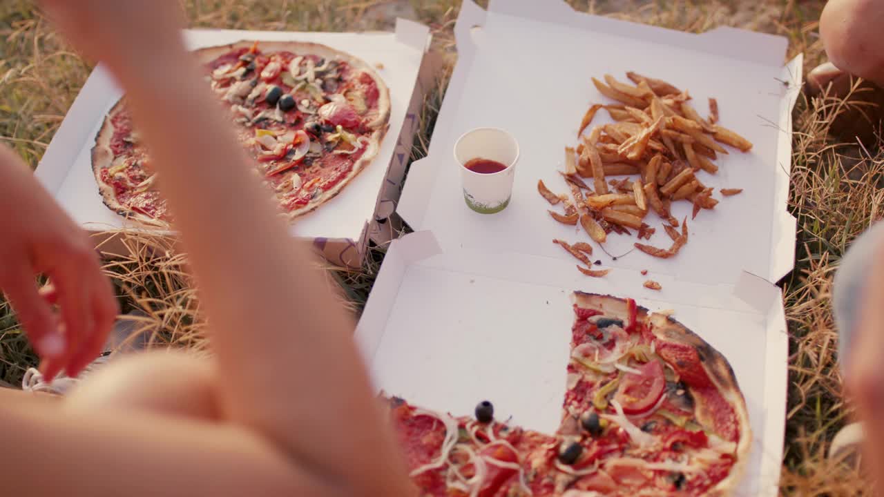 一群朋友在海滩上吃素食披萨和薯条视频下载