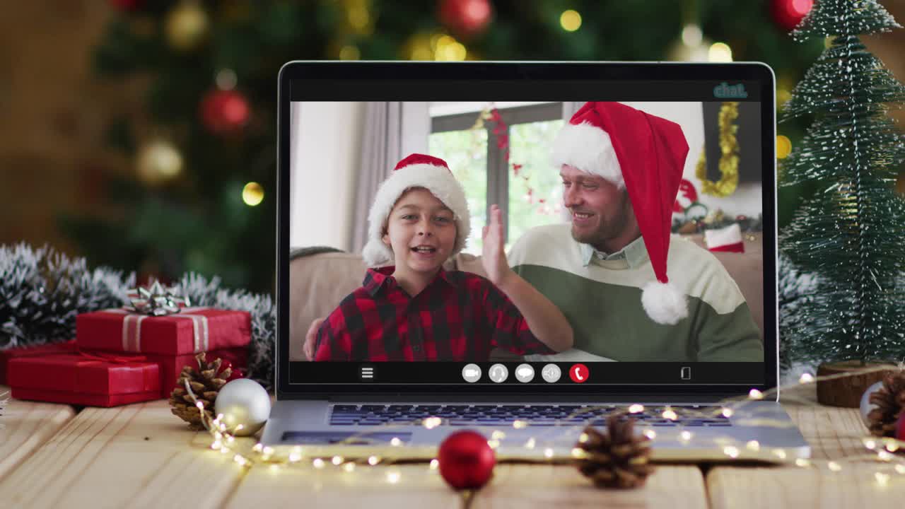 有圣诞装饰和圣诞树的笔记本电脑上，快乐的父亲和儿子在视频通话视频下载
