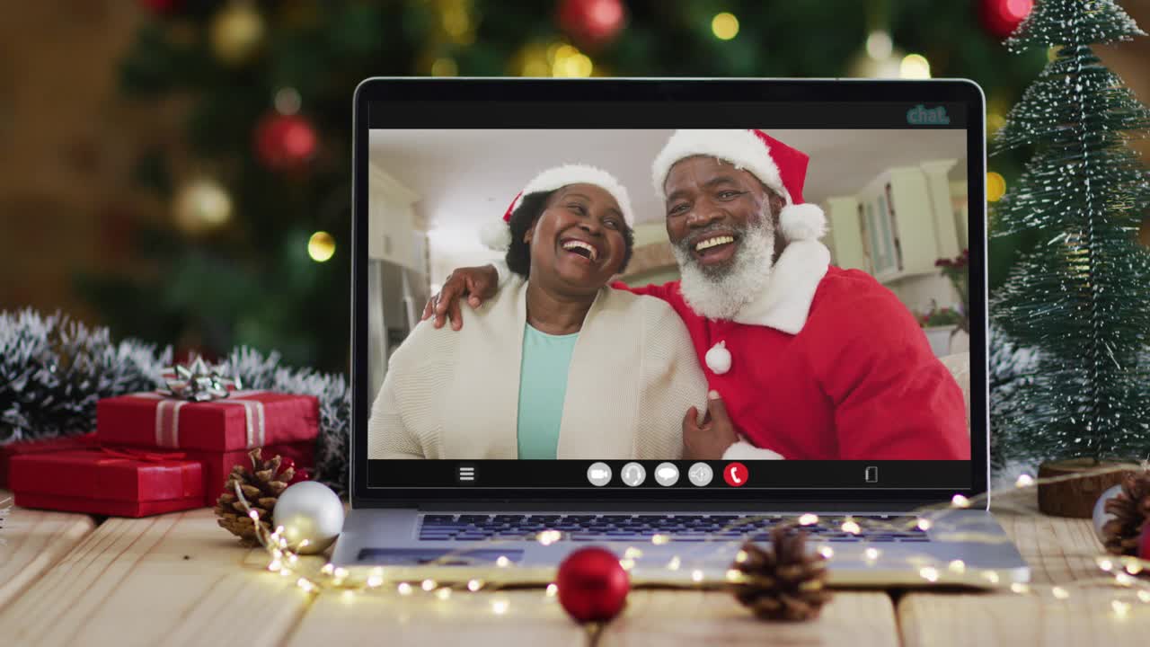 非洲裔美国老夫妇戴着圣诞帽在笔记本电脑上视频通话，有圣诞树视频下载