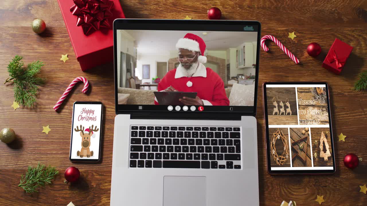 高级非裔美国圣诞老人在笔记本电脑上视频通话，智能手机，平板电脑和装饰视频下载