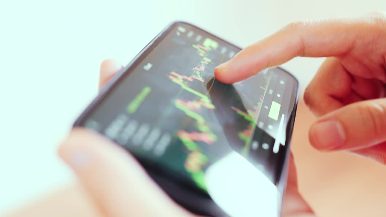 一名女子在智能手机上查看比特币价格图表，预测加密货币未来价格走势。视频素材