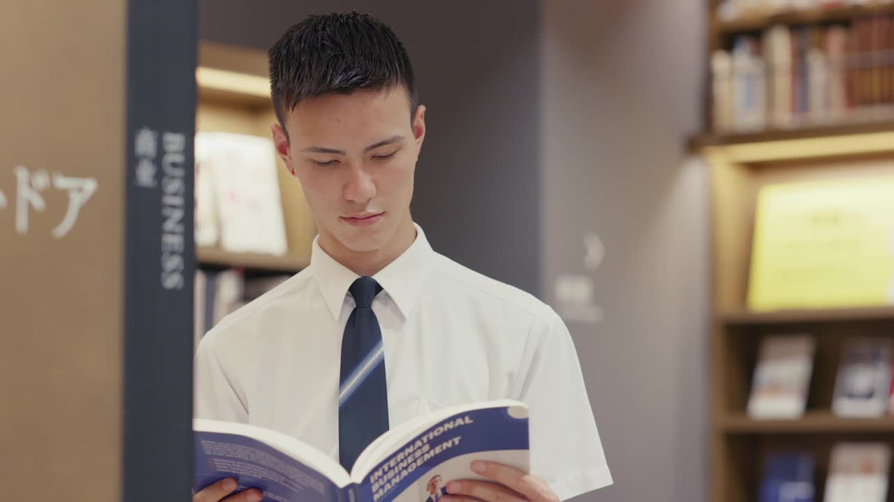 年轻的男学生正在阅读一本商业教科书视频下载