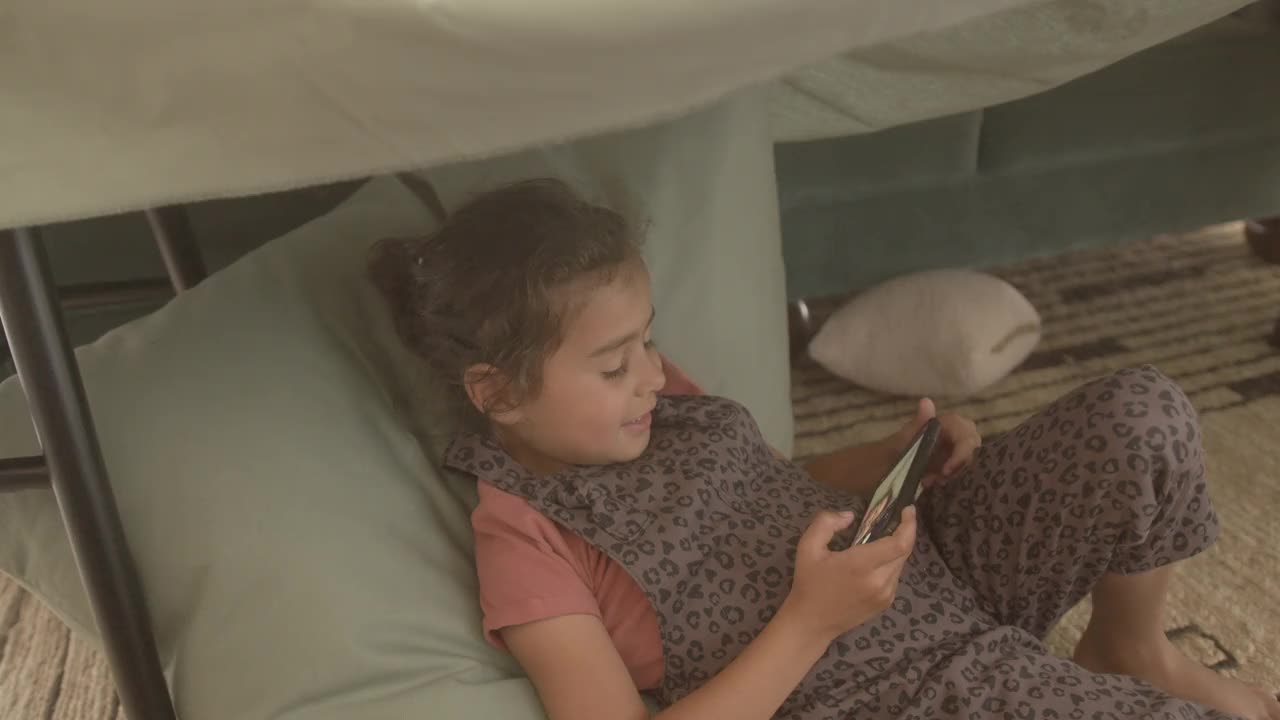 混血女孩在小屋里用智能手机自拍视频下载