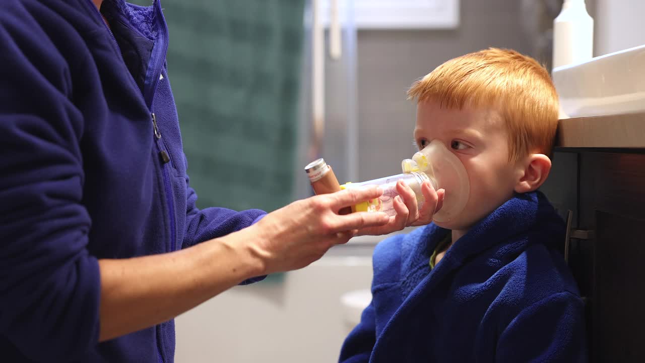 红发小男孩接受母亲的呼吸性哮喘治疗视频素材