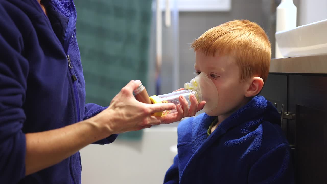 红发小男孩接受母亲的呼吸性哮喘治疗视频素材