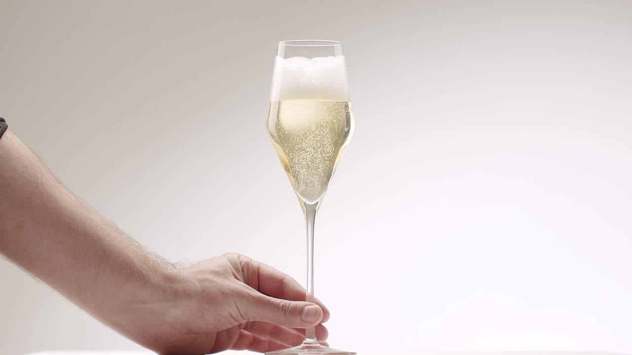 一个男人的手把满满一杯现代香槟放在白色背景上视频素材