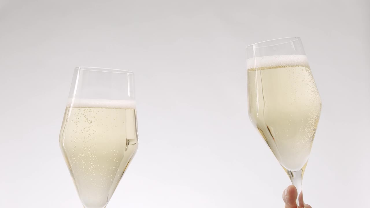 两杯香槟在白色背景下缓缓碰撞视频素材