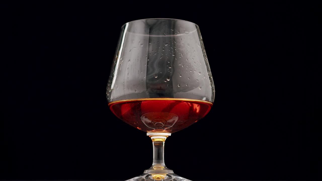 烈性酒精饮料威士忌、白兰地、干邑在玻璃杯中加入冰块视频下载