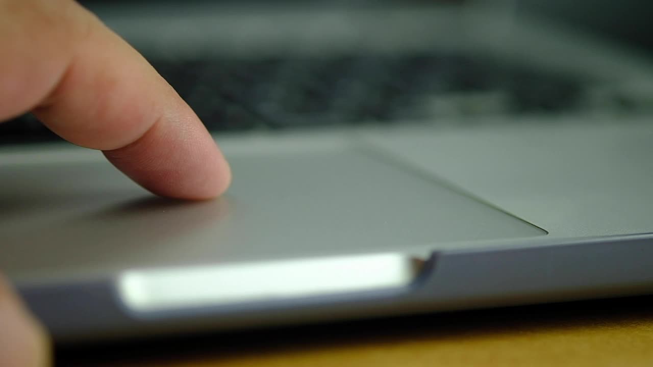使用电脑工作时使用笔记本触摸板的男性手指的特写慢动作视频素材