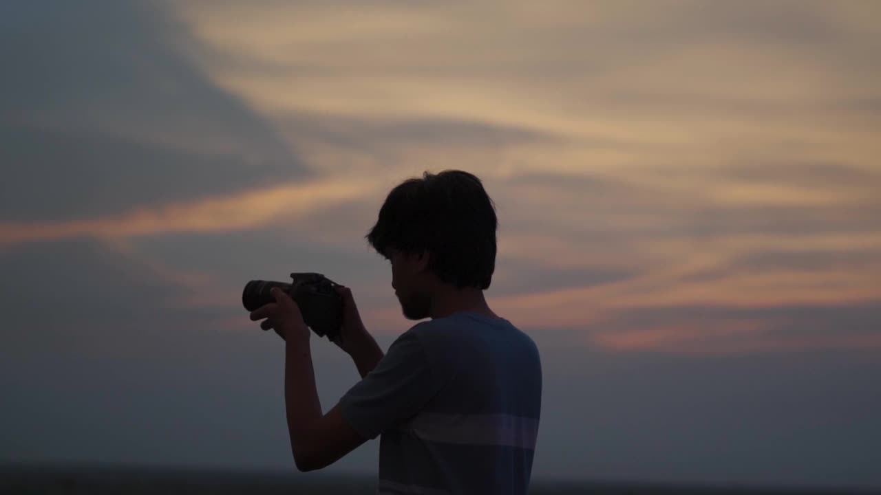 一个印度摄影师在日落时用他的相机拍照的剪影。一个男人在日落时用他的相机拍照。摄影师拿出相机拍照。视频素材