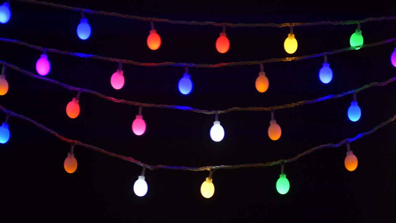 五颜六色的圣诞节日灯串闪烁孤立在黑色背景视频下载