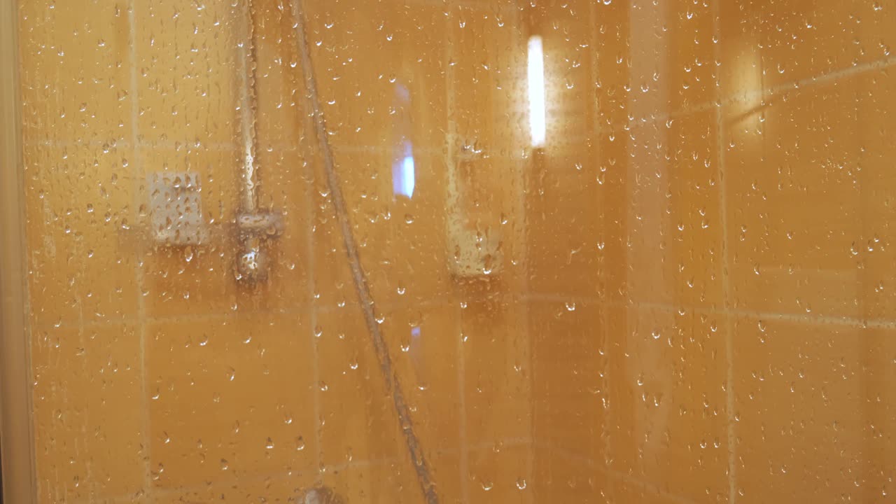 阵雨小屋。雾蒙蒙的淋浴门上的水滴视频素材