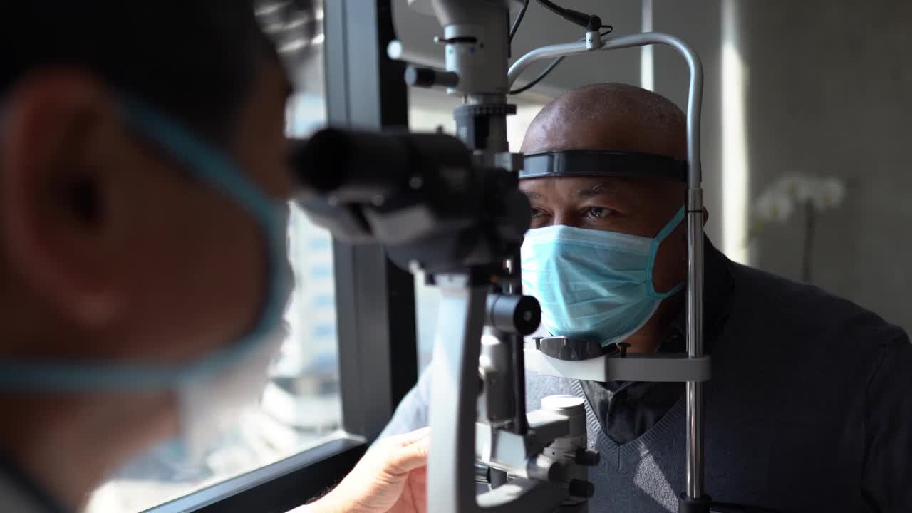 验光师戴防护口罩检查病人眼睛视频下载
