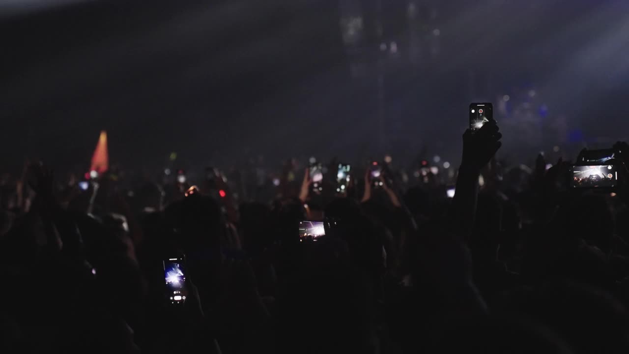 在音乐节上欢呼的人群。专注于跳舞的人用智能手机录音。黑暗的场景视频素材