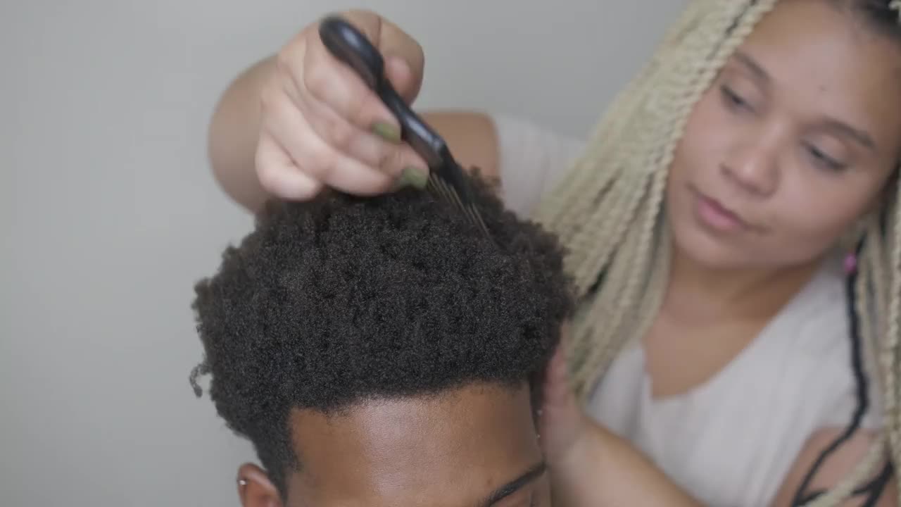 年轻女子为男子梳非洲式发型的细节视频素材