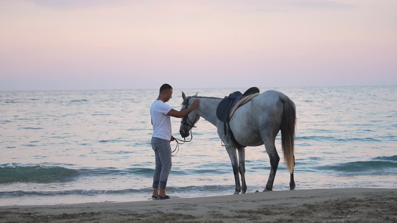 日落时分，一个男人和他的马在海滩上消磨时光。视频下载