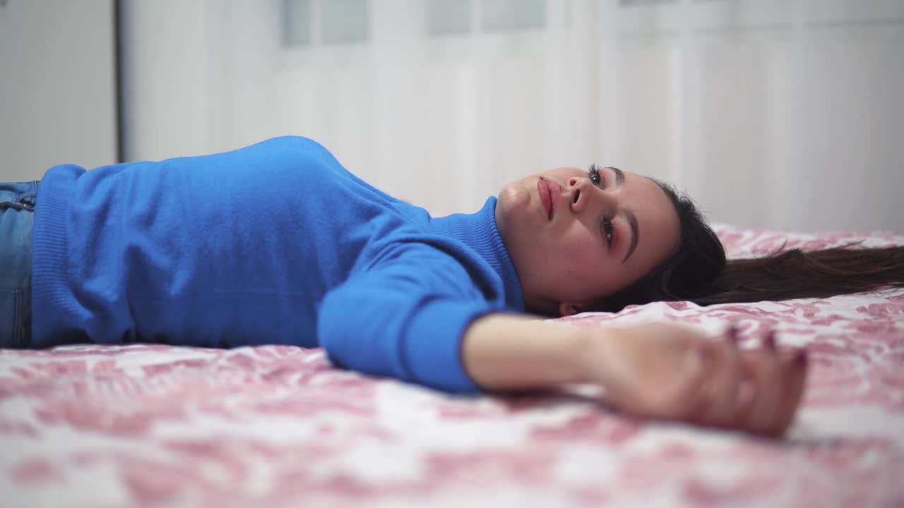 一个体贴的女人躺在家里的床上伸开双臂视频下载