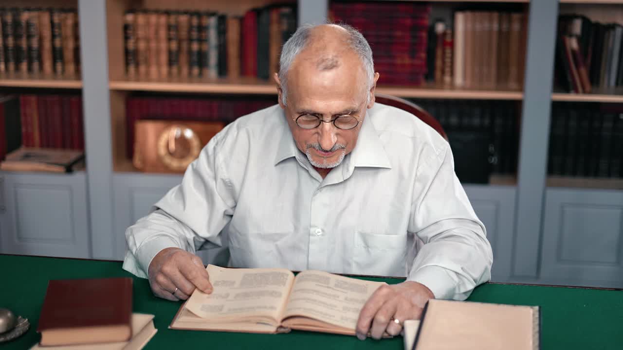 科学家老男博士在公共图书馆书桌前阅读古籍知识视频素材