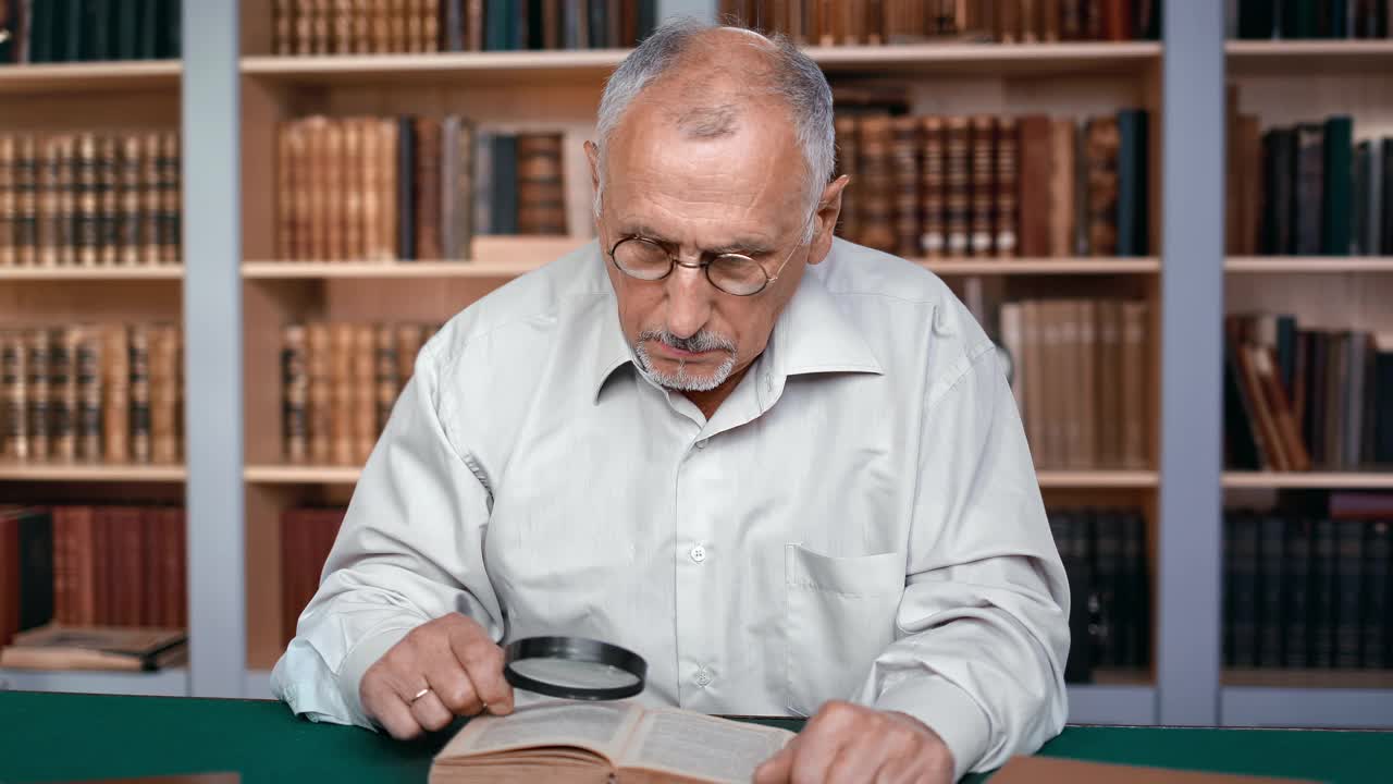 专注的老人70年代科学家在图书馆用放大镜阅读专业书籍视频素材
