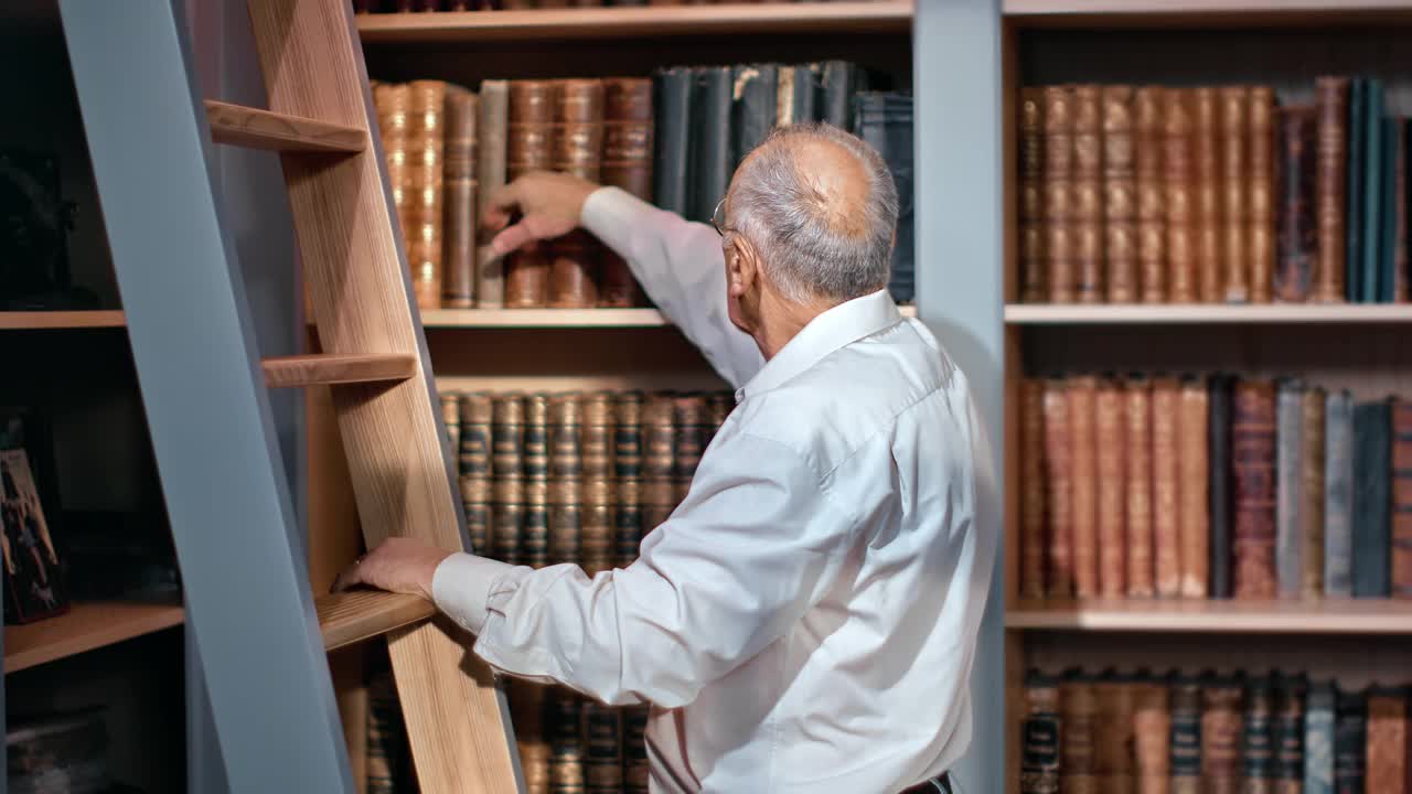 集中灰白头发的70多岁老年男性从储存架公共图书馆选择古董复古书视频素材