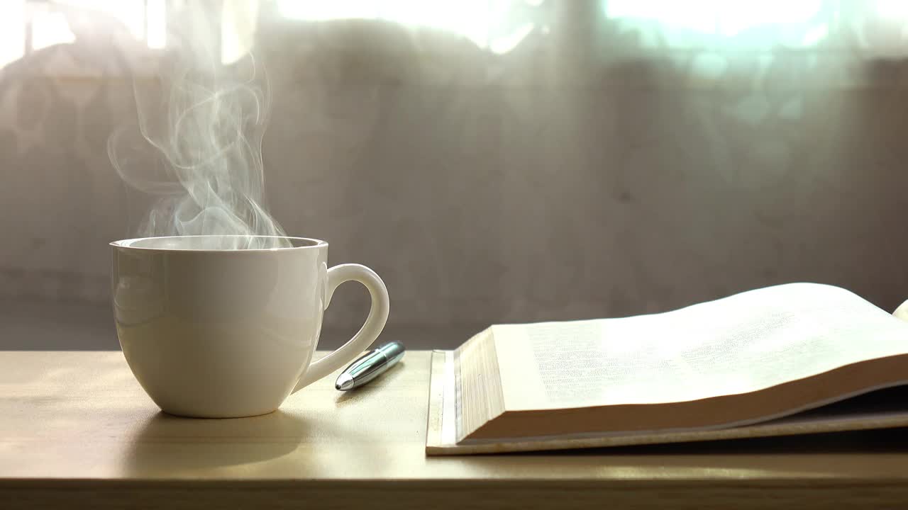一本书和咖啡杯在早晨的烟雾。视频下载