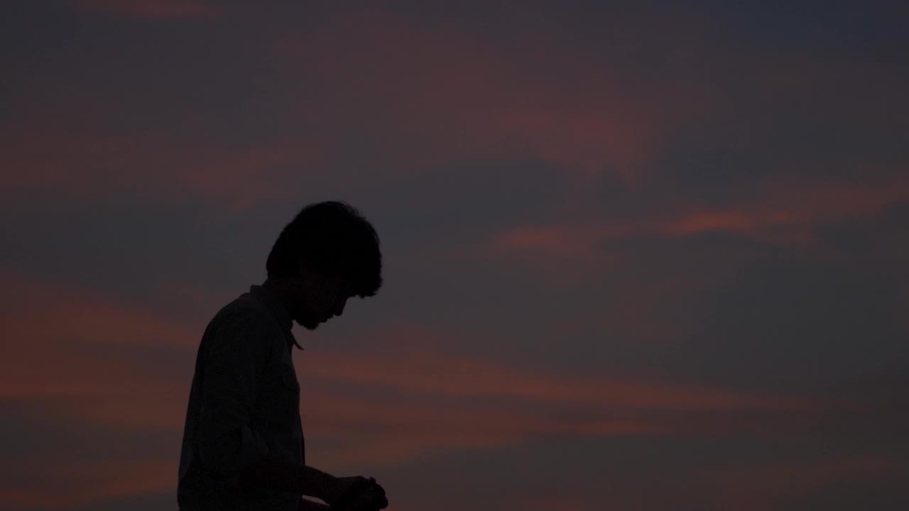 一个印度摄影师在日落时用他的相机拍照的剪影。一个男人在日落时用他的相机拍照。摄影师拿出相机拍照。视频素材