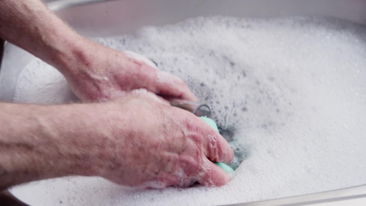退休男子在厨房水槽里手洗盘子视频下载