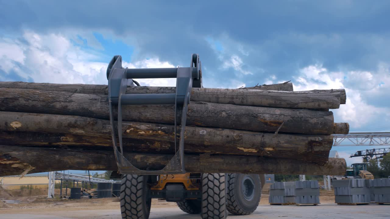 在木工工厂，拖拉机装载机使用抓斗来运输原木视频下载