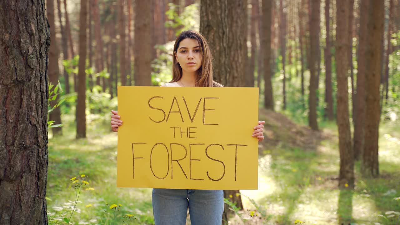 年轻的女志愿者积极分子用海报抗议拯救森林。视频下载