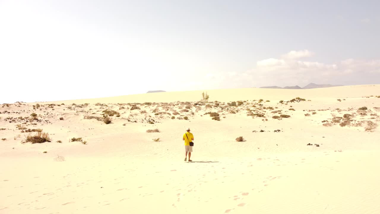 在加那利群岛富埃特文图拉科拉莱霍公园的沙丘上，一名年轻男子驾驶无人机的鸟瞰图。西班牙视频素材
