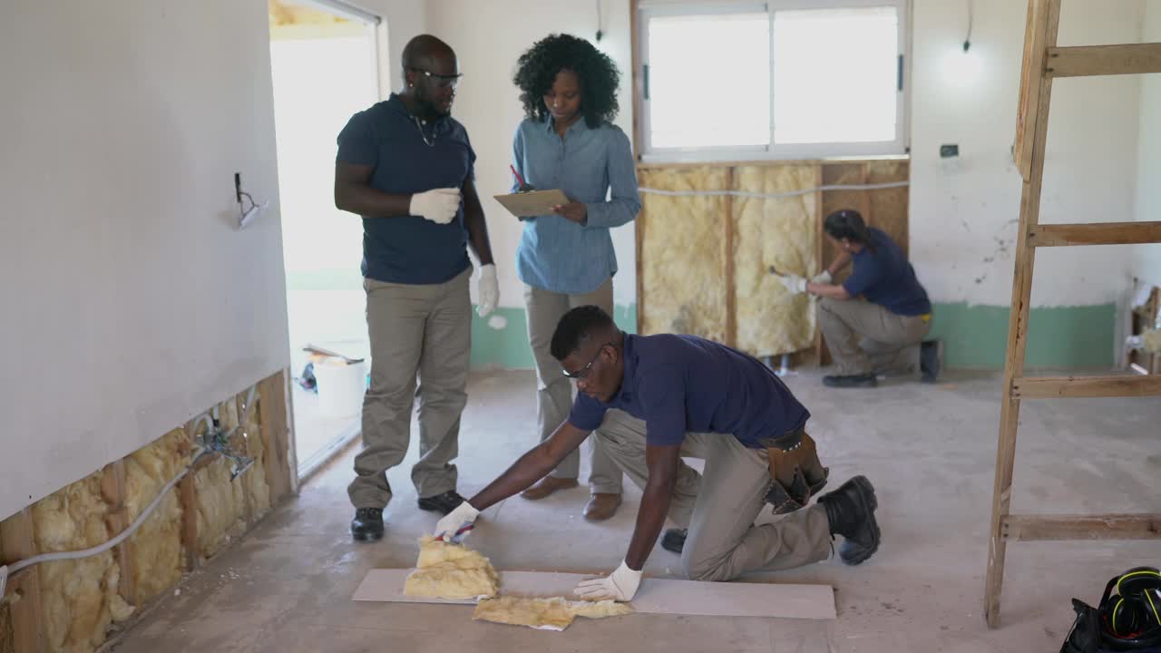 非裔美国女老板在木框架房屋建造期间监督绝缘板的装配视频下载