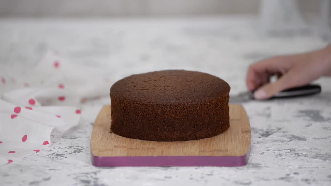 女糕点厨师用刀切巧克力海绵蛋糕，特写镜头。视频素材