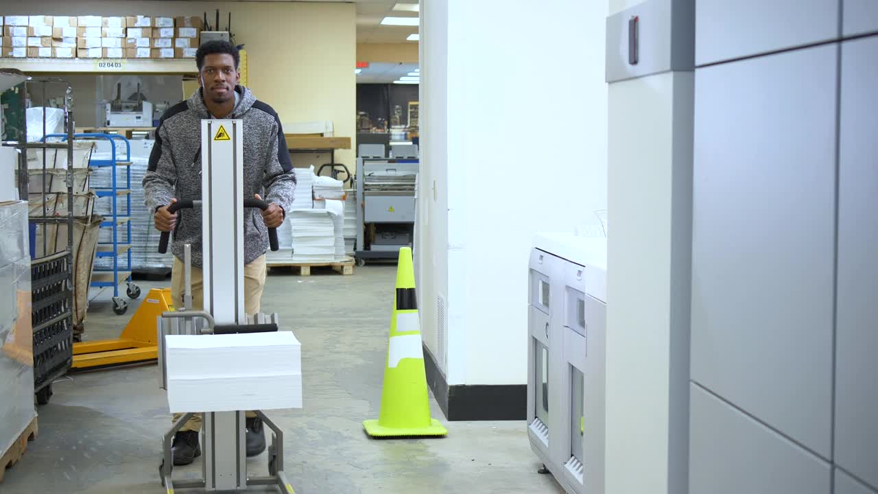 印刷厂工人用手动叉车搬运纸张视频素材