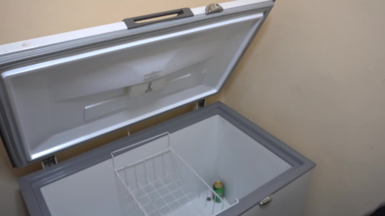 一名男子在晚上把冰袋放进平房的空冰箱里视频下载