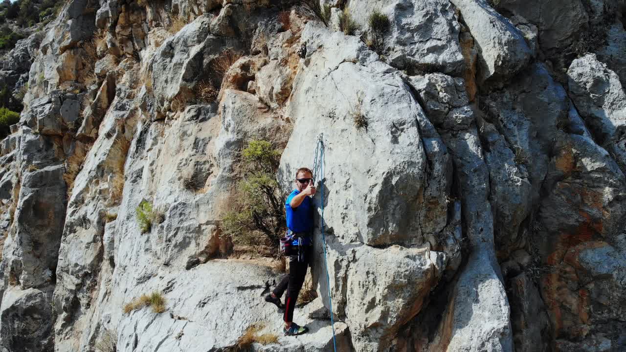 鸟瞰图的女性高山攀岩者正在攀登一座小山的顶峰视频下载