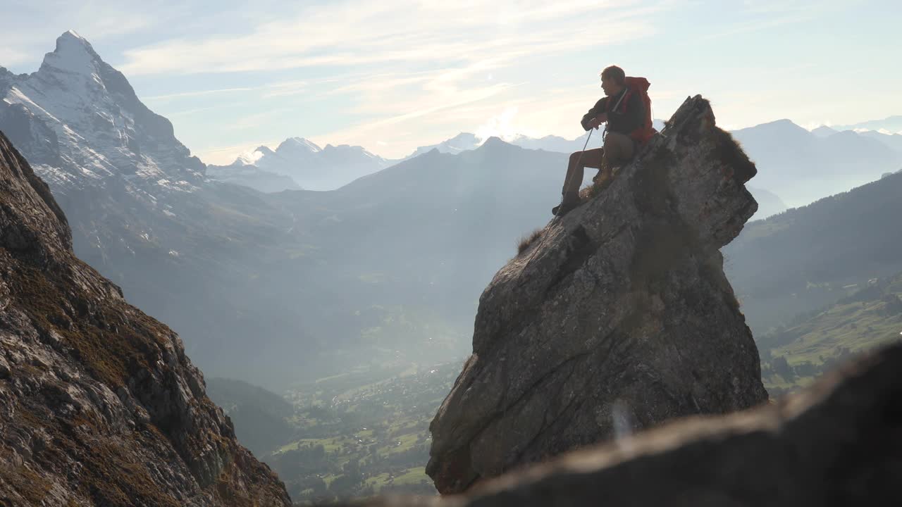 男登山运动员在岩石的顶峰上盘绕绳子视频下载