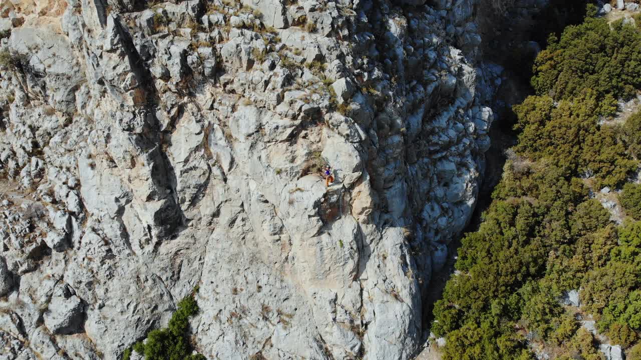 鸟瞰图的女性高山攀岩者正在攀登一座小山的顶峰视频下载