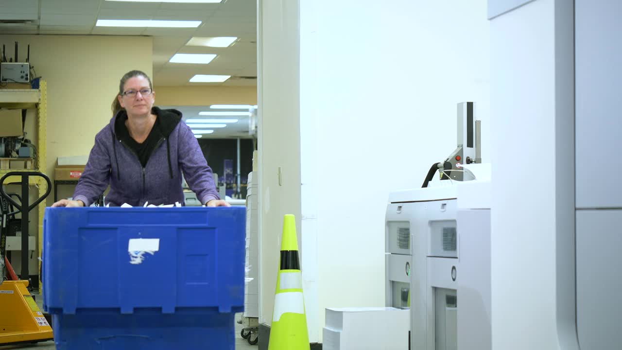 妇女在印刷厂与回收箱，纸屑视频素材